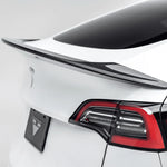A close up view of Vorsteiner VRS Aero Decklid Spoiler Carbon Fiber PP 2x2 Glossy fitted on a white car (for Model Y).