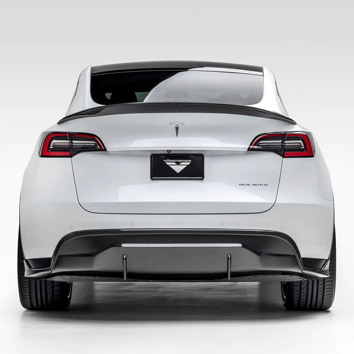 A wide view of Vorsteiner VRS Aero Rear Diffuser Carbon Fiber PP 2x2 Glossy fitted on white car from behind (for Model Y).