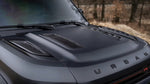 A front close up view of Urban Automotive XRS Limited Edition Carbon Vented Hood for Land Rover L663 Land Rover Defender 90 / 110 / 130 2020-2025 fitted in a car