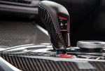 A close up view of AUTOTECKNIC DRY CARBON GEAR SELECTOR COVER for BMW Models fitted in a car
