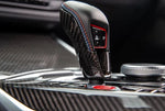A close up view of AUTOTECKNIC DRY CARBON GEAR SELECTOR COVER for BMW Models fitted in a car