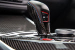 A close up view of AUTOTECKNIC DRY CARBON GEAR SELECTOR COVER for BMW Models fitted in a car