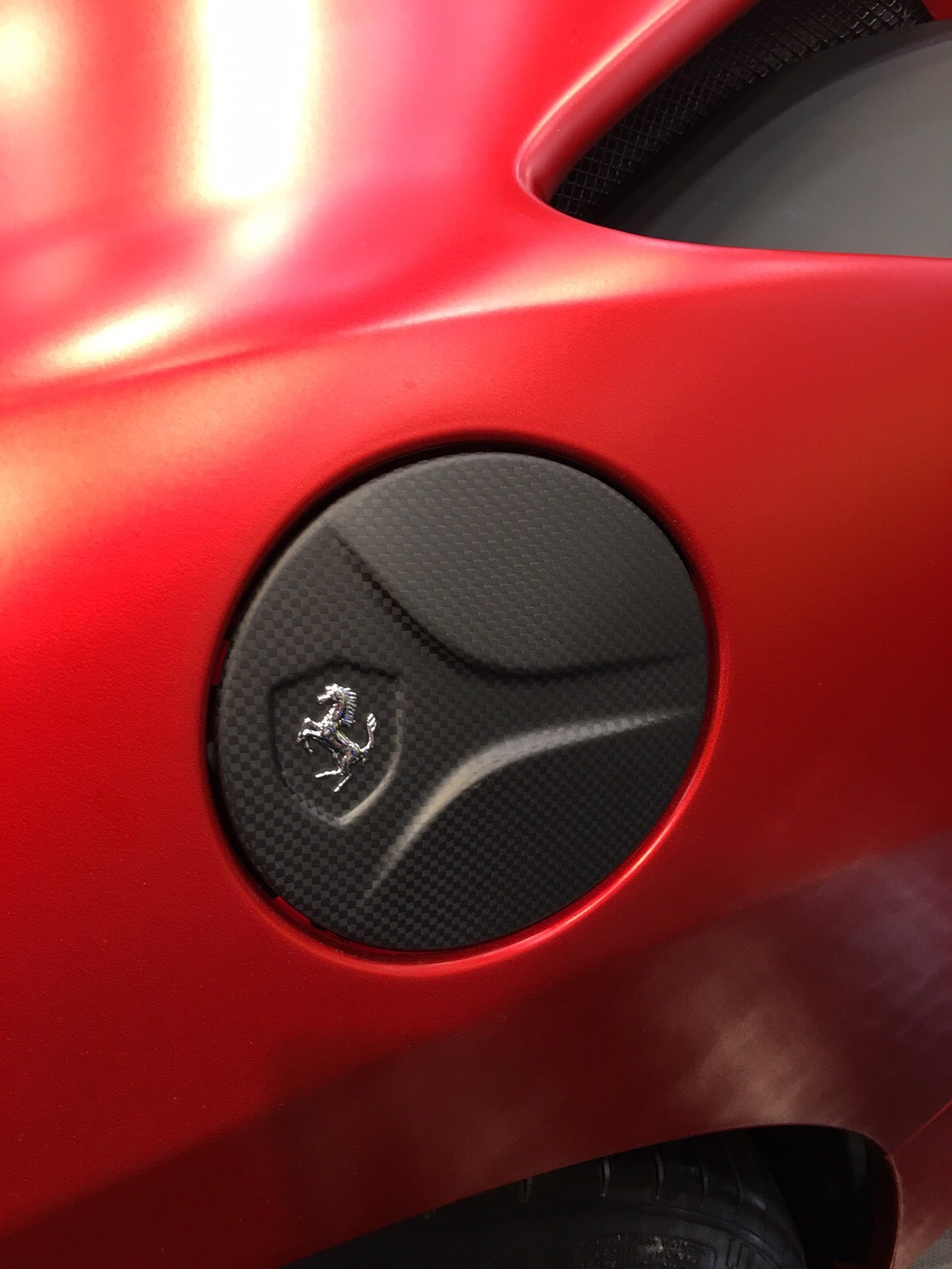Capristo carbon fiber gas cap for the Ferrari 488 in matte carbon on a red car