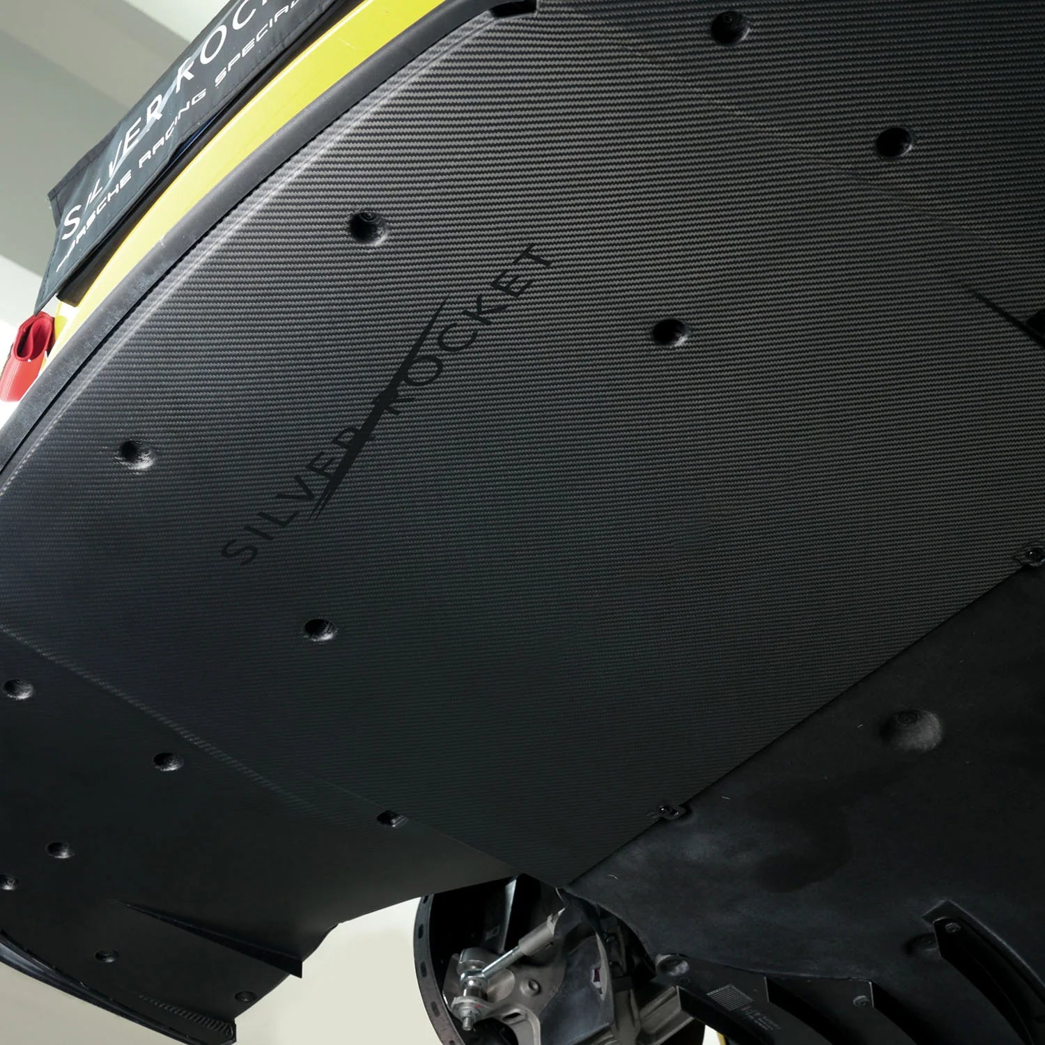 Angled close-up of installed dry carbon fiber aeroshield panel with visible twill weave pattern, recessed mounting fasteners, and contoured edge profile - SilverRocket Ultra Downforce Front Aeroshield Porsche 718 GT4 RS