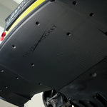 Angled close-up of installed dry carbon fiber aeroshield panel with visible twill weave pattern, recessed mounting fasteners, and contoured edge profile - SilverRocket Ultra Downforce Front Aeroshield Porsche 718 GT4 RS