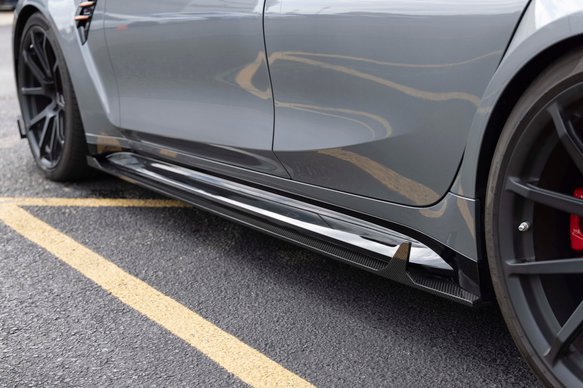 A close up view of DINAN SIDE SKIRTS BMW M3/M4 2021-2024 fitted on a car