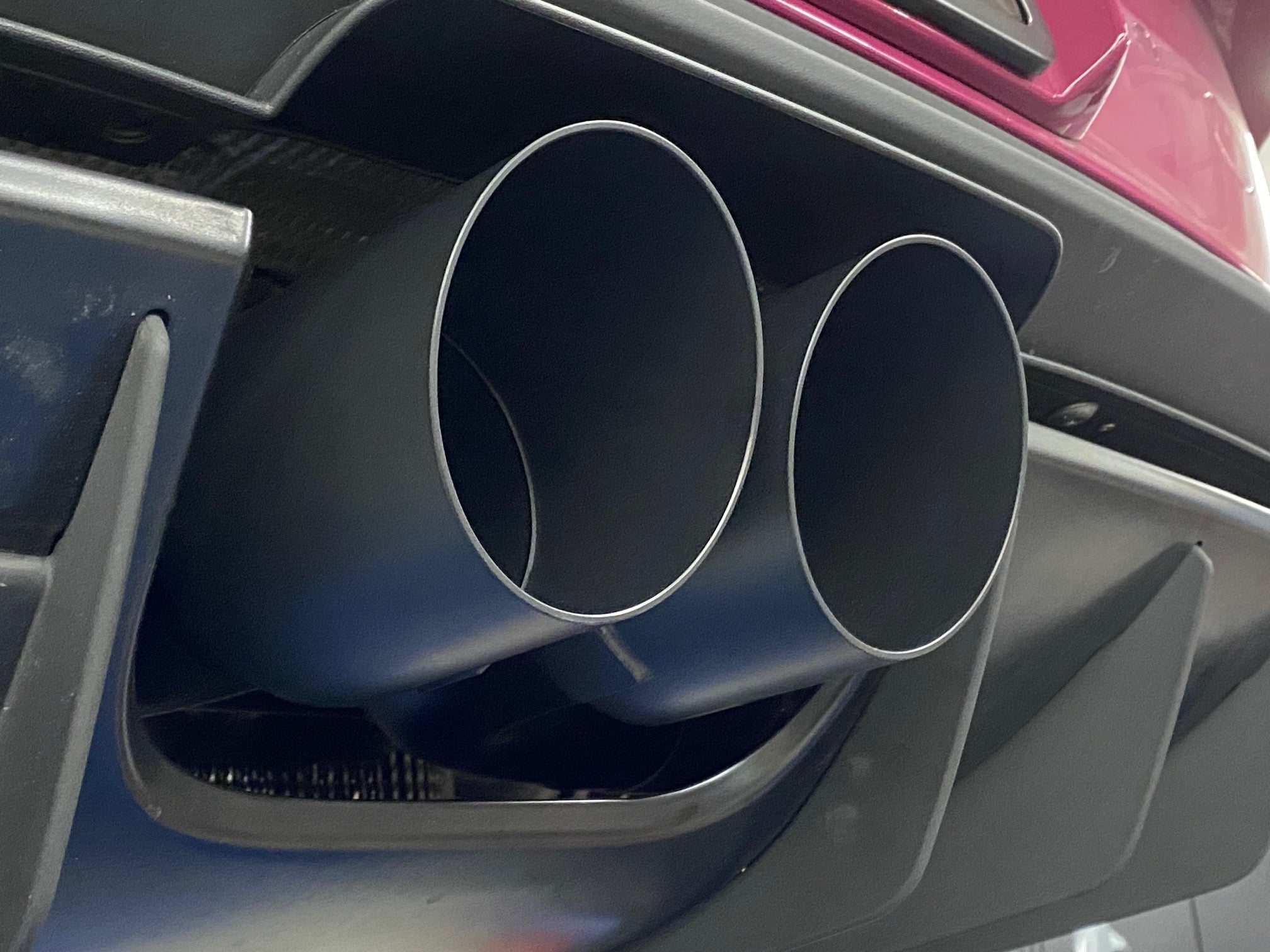 A close up view of Shark Werks Exhaust System for Porsche 992 GT3 / GT3RS exhaust tips in Black fitted on a car