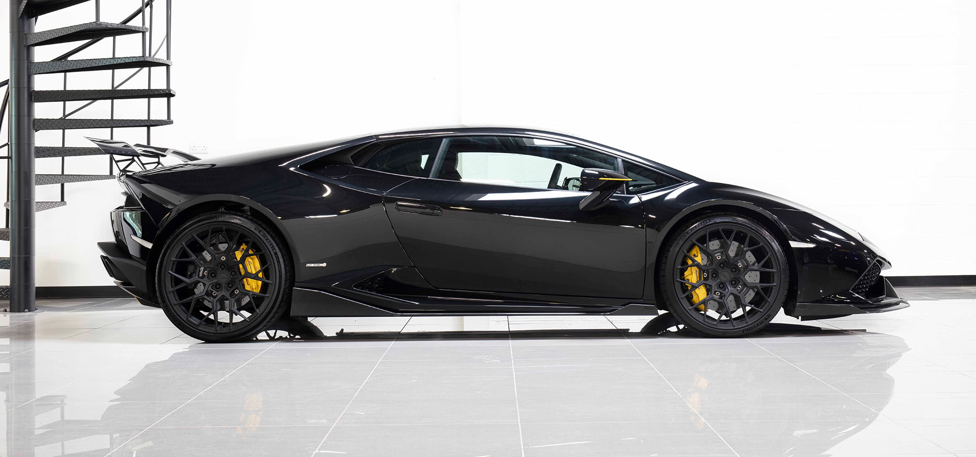 Rear three-quarter view of a black Lamborghini Huracan with the Urban carbon rear wing
