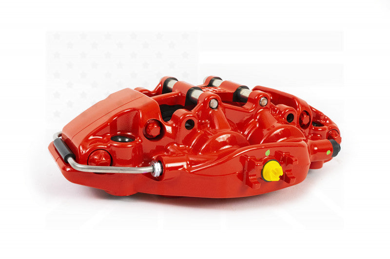 A side view of the red caliper of the AP Racing by Essex Road Brake Kit (Rear 9541/380mm)- C6 Corvette with a white background