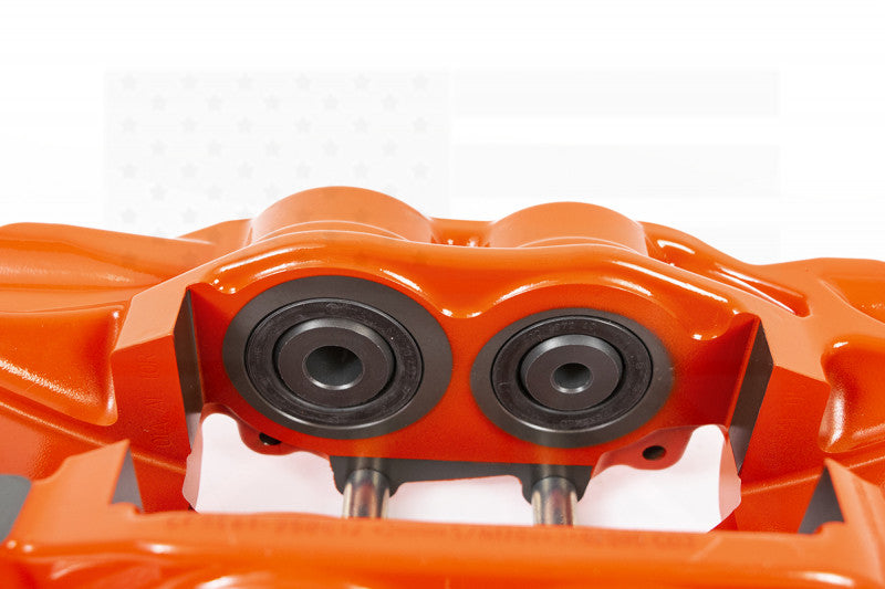 A close up view of the red caliper of the AP Racing by Essex Road Brake Kit (Rear 9541/380mm)- C7 Corvette with a white background