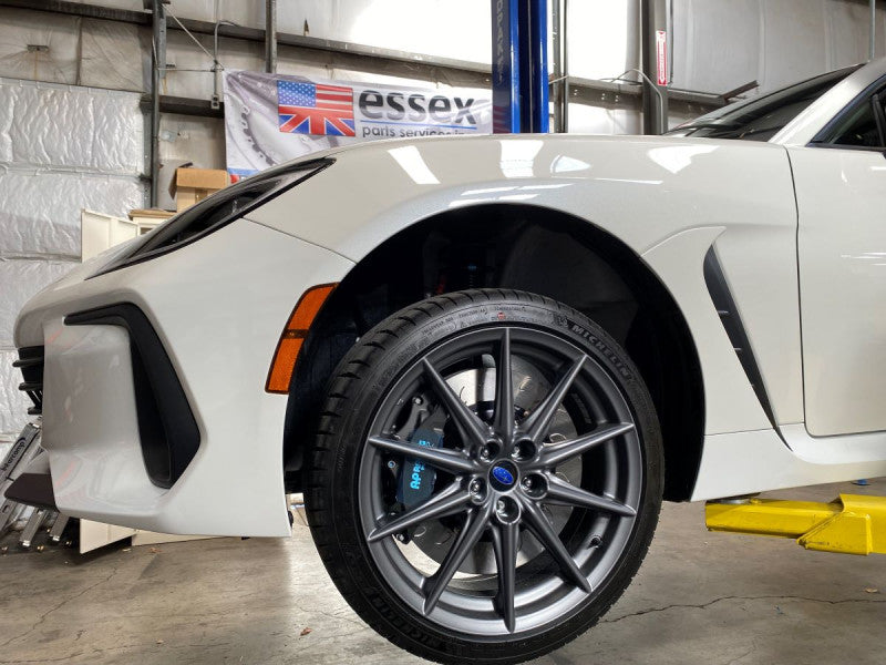 A close up view of a white car with the front wheel fitted with AP Racing by Essex Radi-CAL Competition Brake Kit (Front CP9668/372mm) - Subaru BRZ, Scion FR-S & Toyota GT86/GR86 2013+
