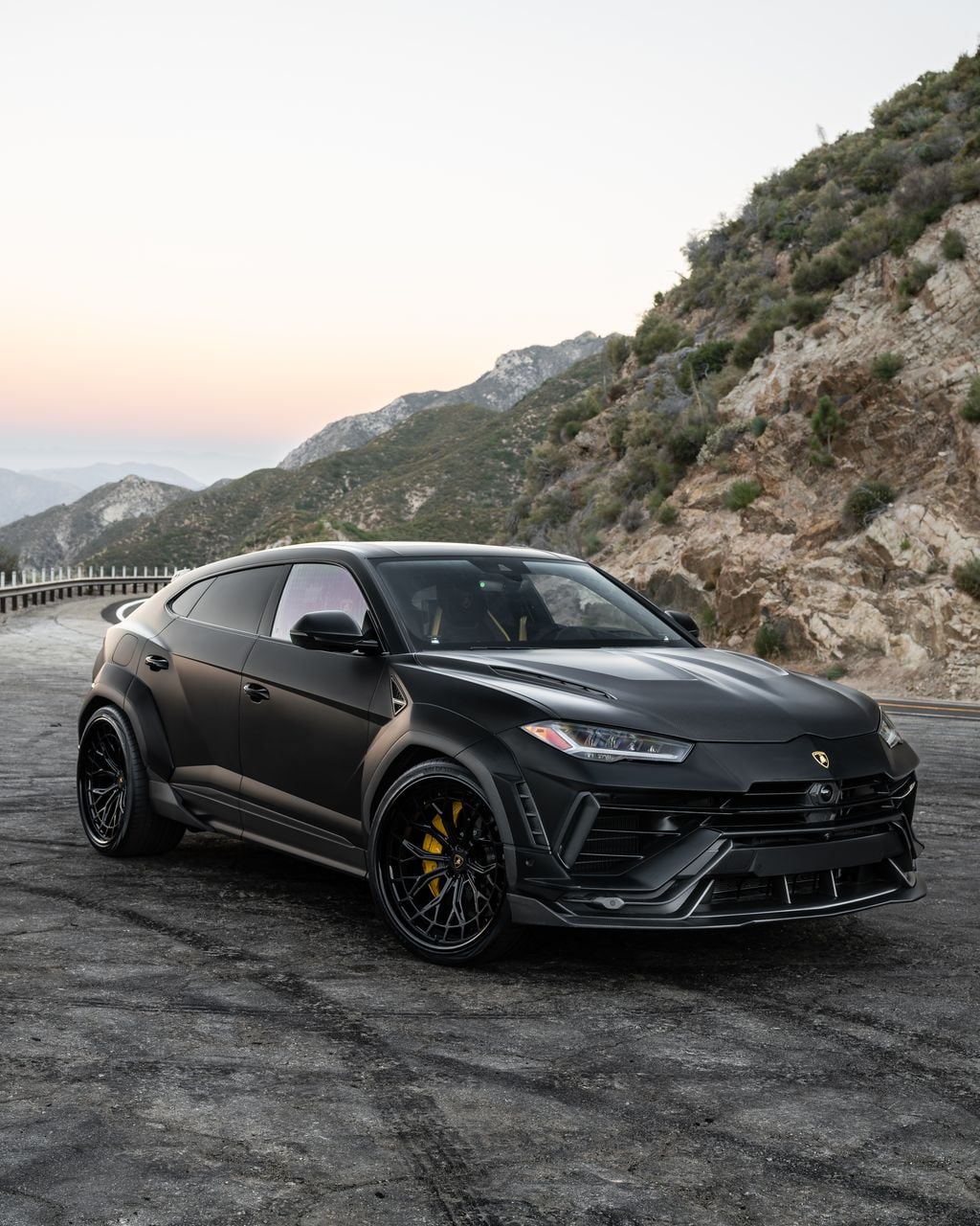 Black Lamborghini Urus front three-quarter on a mountain road