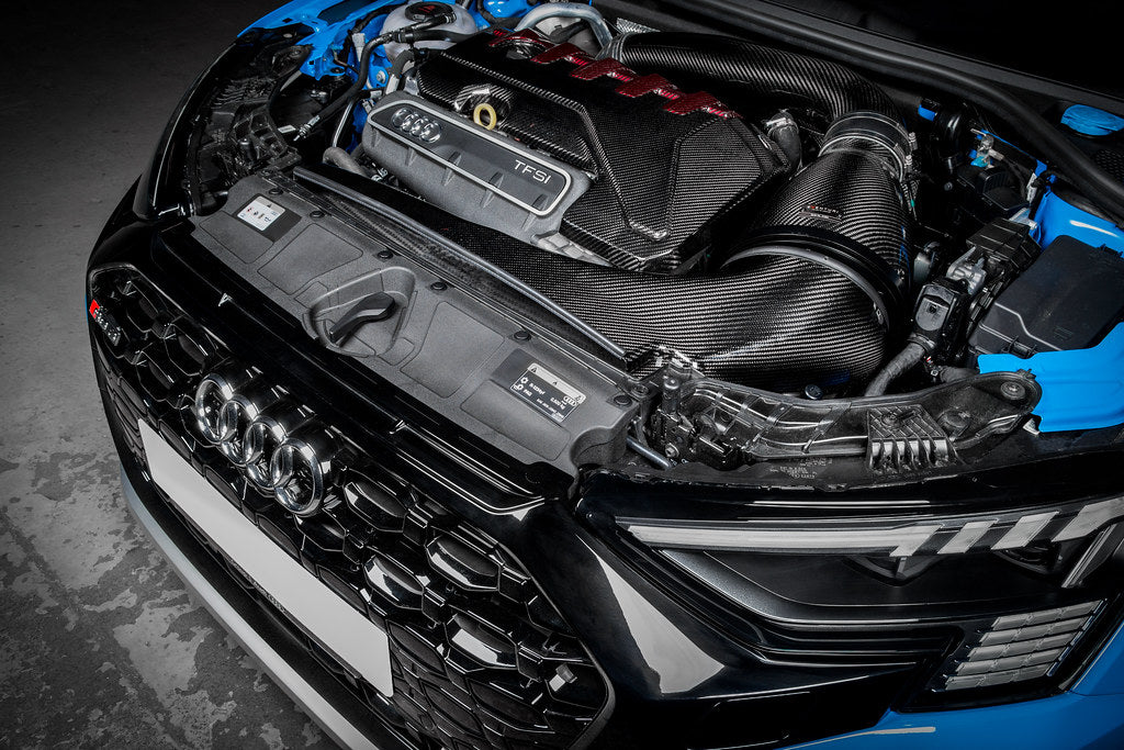 Carbon fiber intake system installed in engine bay with curved intake tubes and turbo engine visible - Eventuri intake for Audi RS3