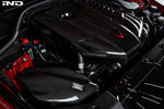 Carbon fiber intake system with curved ducting and filter housing installed in engine bay with red arrow graphic overlay - Eventuri intake for Toyota Supra