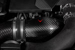 Carbon fiber turbo inlet tubes installed in BMW engine bay with red arrow pointing to component - Eventuri turbo inlet set for BMW F90 M5 F91 F92 F93 M8