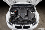 Carbon fiber airbox lid installed in white BMW M3 engine bay with hood open showing complete engine compartment - Eventuri airbox lid for BMW M3