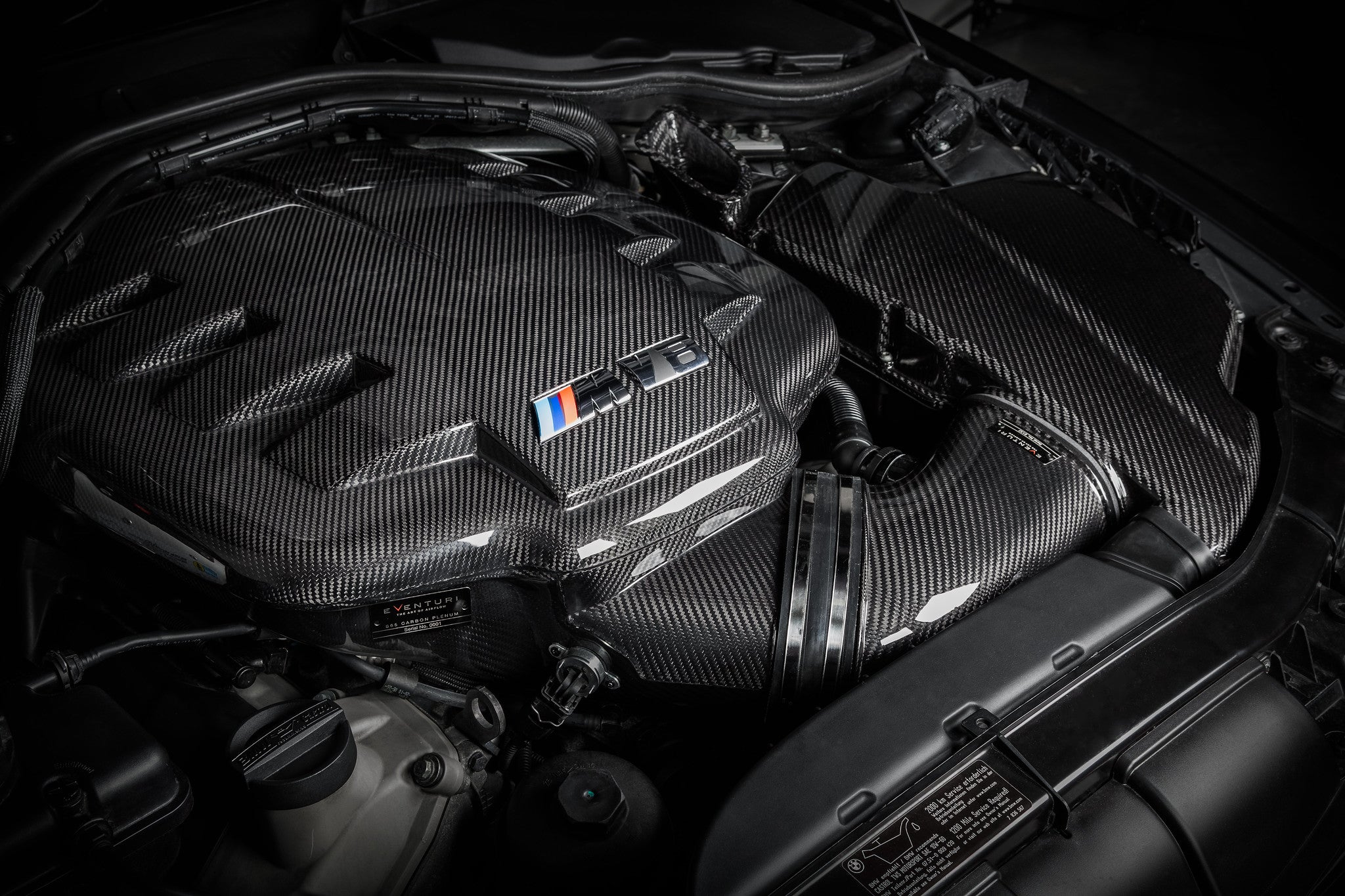 Carbon fiber inlet plenum with angular geometric design installed in engine bay with intake tubes connected - Eventuri inlet plenum for BMW M3