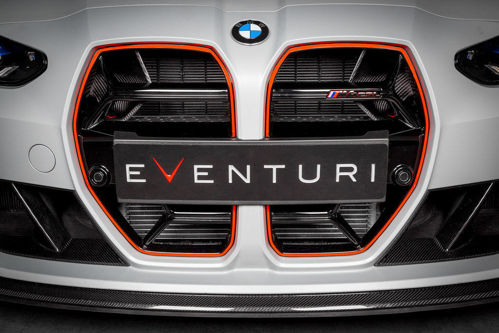 Black carbon fiber intake scoop installed in front grille opening with angular design and visible mounting hardware - Eventuri intake scoop for BMW M3