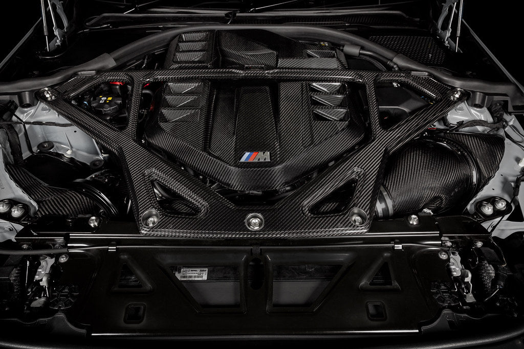 Black carbon fiber strut brace mounted across engine bay strut towers with aluminum brackets and hardware - Eventuri strut brace for BMW M2