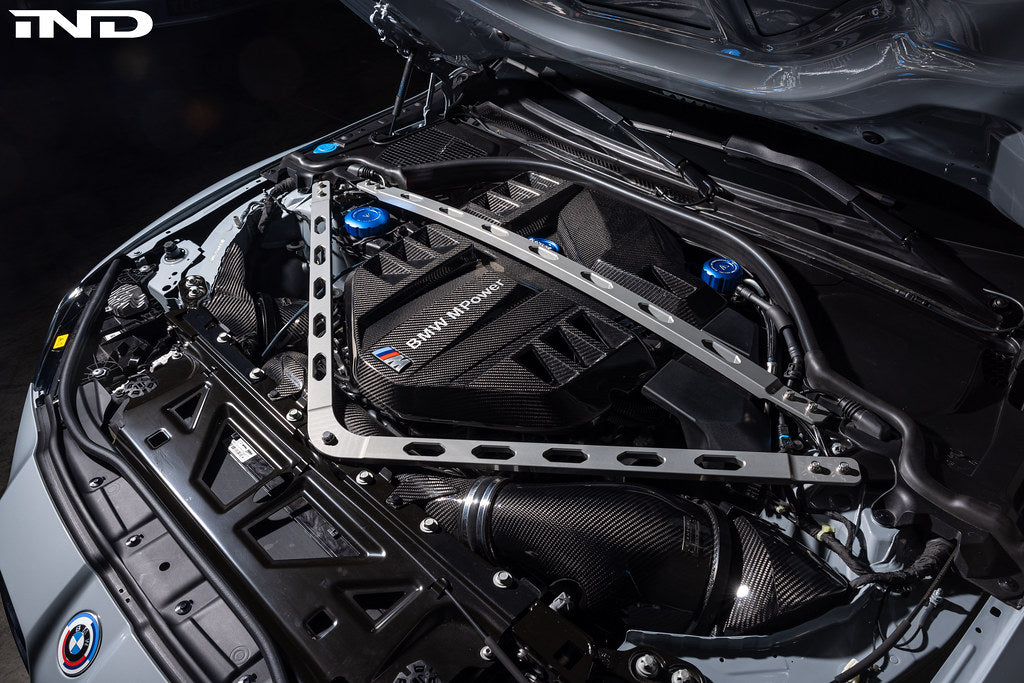 Carbon fiber engine cover installed in BMW M2 engine bay with strut tower brace visible - Eventuri engine cover for BMW M2