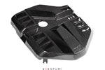 Black carbon fiber engine cover with geometric angular design and central circular opening on white background - Eventuri engine cover for BMW M2