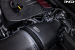 Carbon fiber intake system with cylindrical air filter installed in GR Corolla engine bay showing detailed weave pattern - Eventuri carbon intake for Toyota GR Corolla