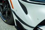 A side close up view of AUTOTECKNIC FRONT BUMPER DRY CARBON CANARD SET - TOYOTA A90 SUPRA 2020+ fitted on a white car