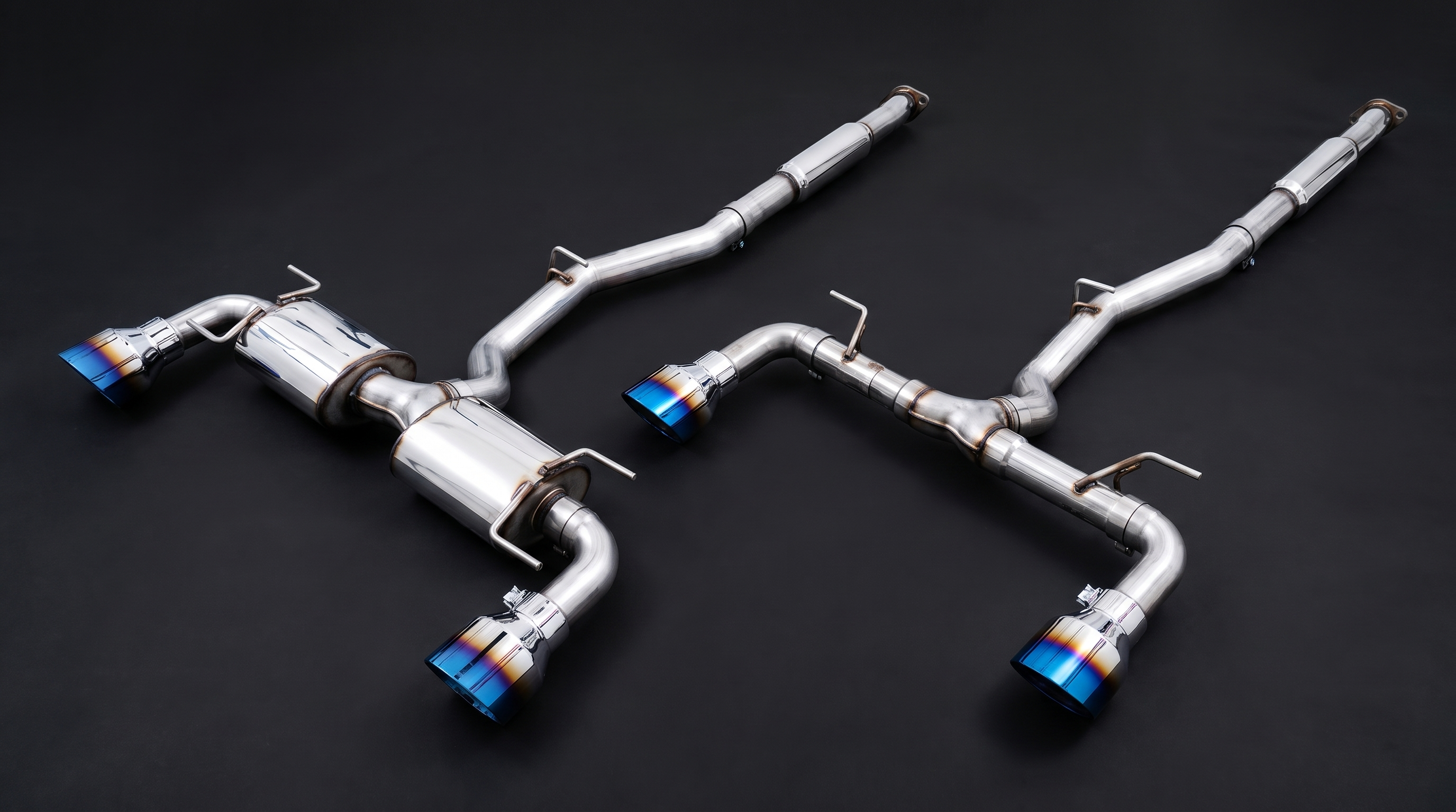 Studio comparison photograph of two AWE-style cat-back exhaust systems for the 86 platform side by side, the resonated Touring-style layout on the left and the straighter Track-style layout on the right, both with blue-tinted slash-cut tips