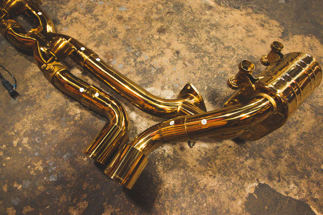 A top overview of Valvetronic Designs Valved Sport Exhaust System's exhaust tips and muffler on the ground (for Porsche 911 Carrera / S / GTS, Targa 4 / S / GTS).