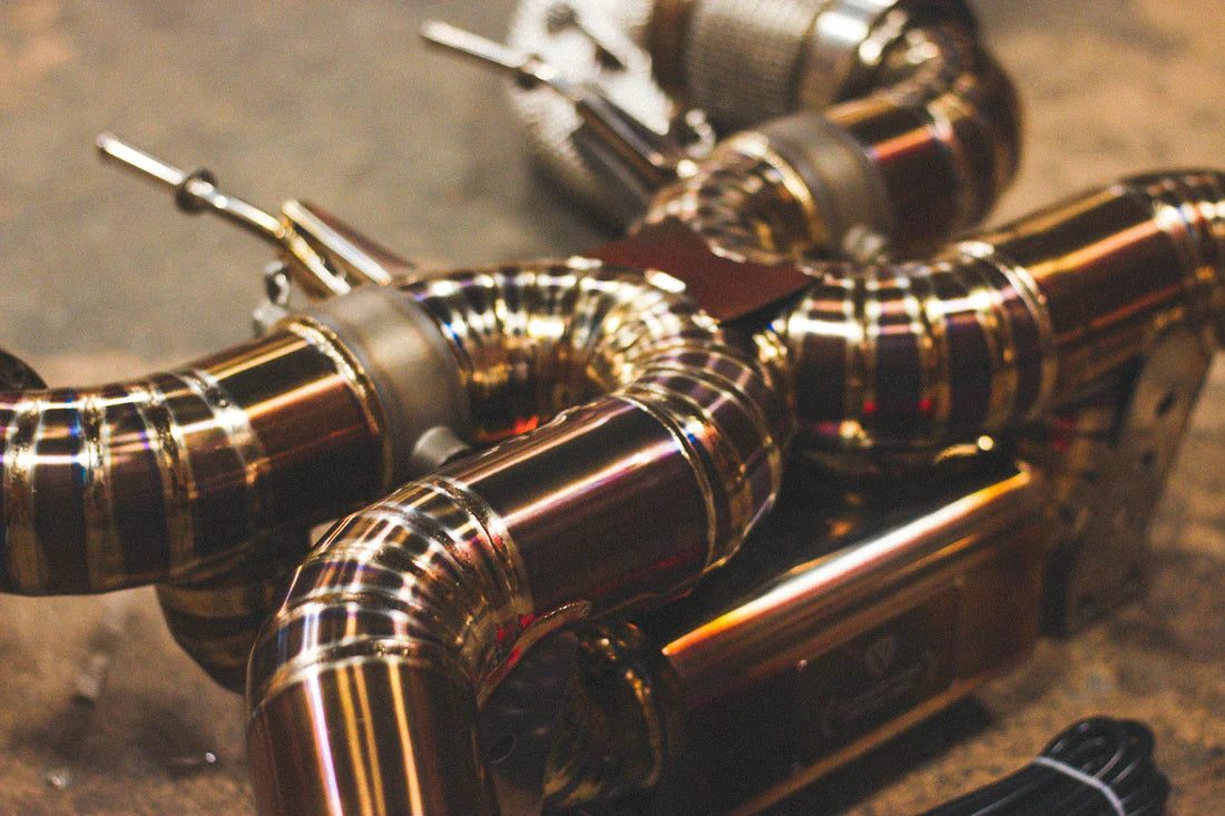 A close up view of Valvetronic Designs Titanium Valved Sport Exhaust System on the ground (for Mclaren 720S).