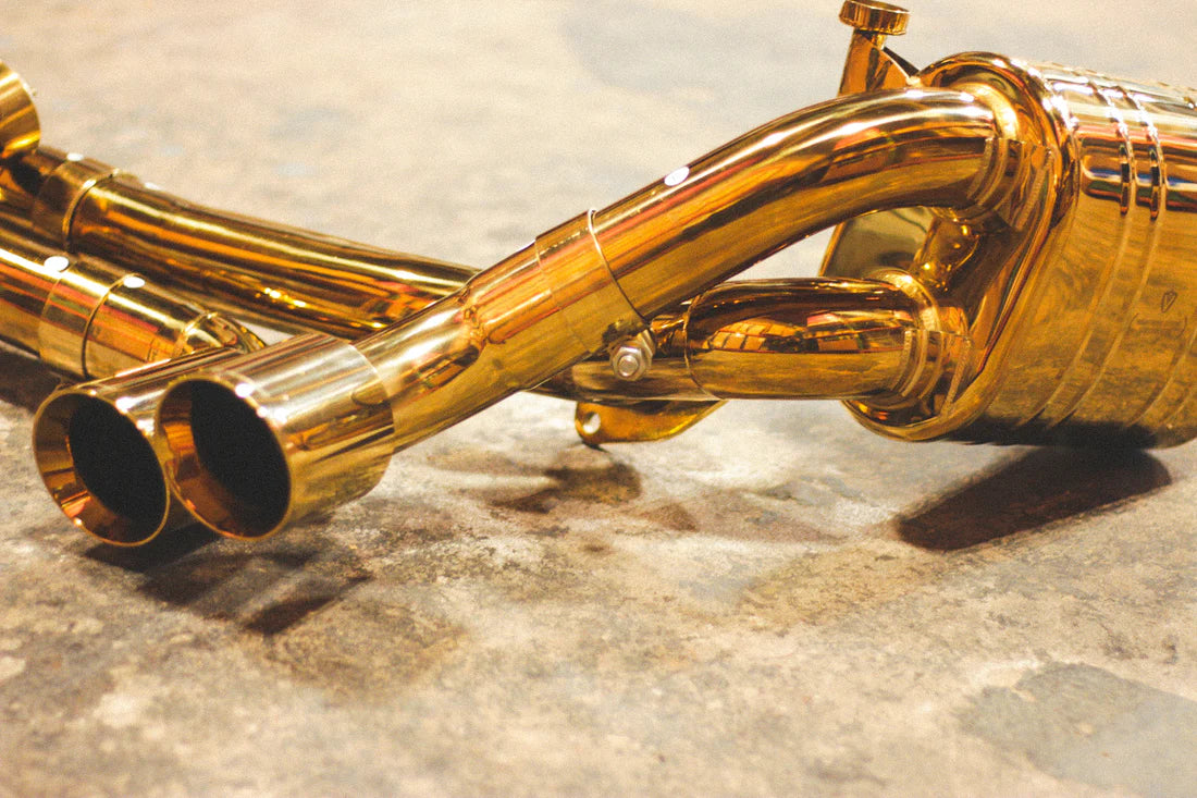 A close up view of Valvetronic Designs Valved Sport Exhaust System's exhaust tips and muffler on the ground (for Porsche 911 Carrera / S / GTS, Targa 4 / S / GTS).