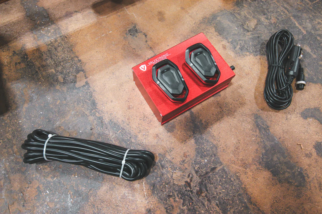 A close up view of Valvetronic Designs Valved Sport Exhaust System's valve controllers and wires on the ground (for Ferrari 488 GTB and Pista).