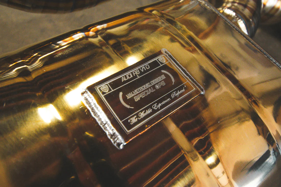 A part Valvetronic Designs gold Valved Sport Exhaust System (for Audi R8 V10 Gen 2 2017+)  on the ground.