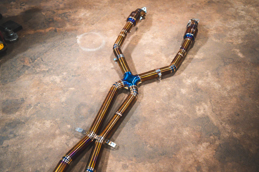 A wide view from the top of Valvetronic Designs Titanium Valved Sport Exhaust System's pipes on the ground (for BMW M3 E9X).