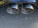 A close up view of Shark Werks Track Exhaust for Porsche 997 / 997.2 GT3 / RS exhaust tips fitted on a car on the ground