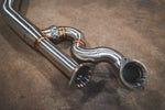 A close up view of Valvetronic Designs Equal Length Midpipe in Brushed Stainless Steel on the ground (for BMW G8x M3 / M4).