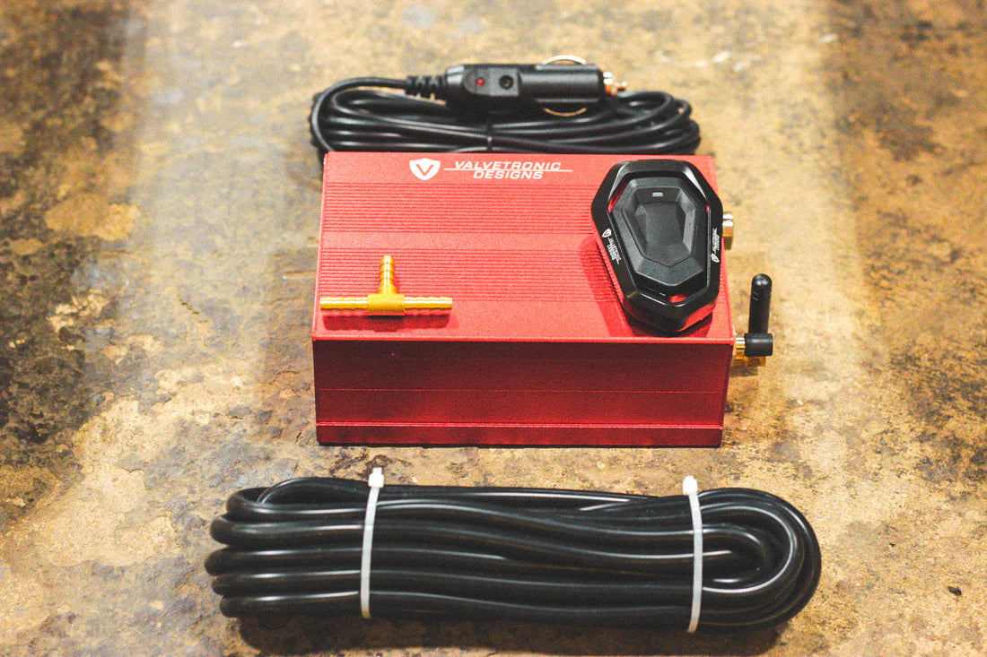 A close up view of Valvetronic Designs Valved Sport Exhaust System's valve controller and wires on the ground (for Mercedes SLS AMG).