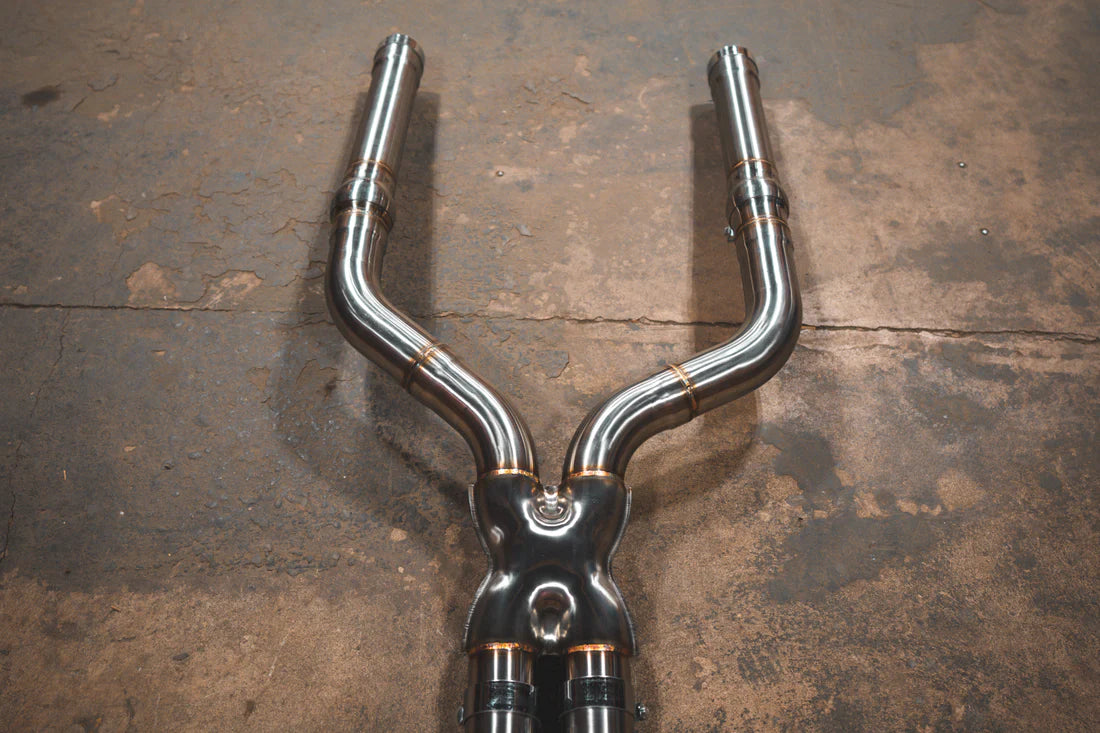 A close view of Valvetronic Designs Valved Sport Exhaust System's pipes on the ground (for BMW F90 M5). 