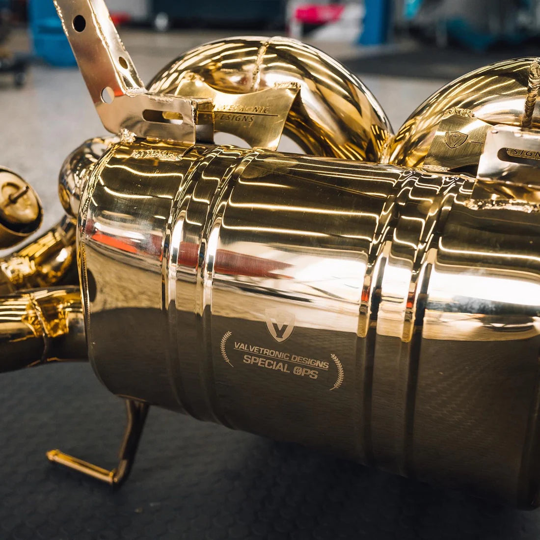 A close up of Valvetronic Designs Valved Sport Exhaust System's muffler on a grey carpet on the ground (for Lamborghini Aventador LP700 / SV).