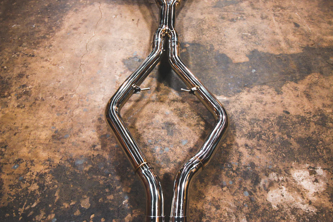 A close up view of Valvetronic Designs Valved Sport Exhaust System's pipes on the ground (for BMW X5M F85 / X6M F86).