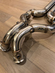 A close up view of Valvetronic Designs Free Flow Front Pipes on a wooden floor (for Mercedes AMG GT/ GTC / GTR).