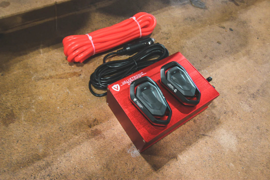 A close up view of Valvetronic Designs Valved Sport Exhaust System's valve controllers and wires on the ground (for Porsche 991 GT3 / RS).