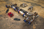 A side overview of Valvetronic Designs Valved Race Exhaust System with valve controllers and free flow headers on the ground (for Porsche 991 Turbo / Turbo S).