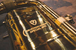 A close up view of Valvetronic Designs Valved Sport Exhaust System's muffler, showing the brand's logo, on the ground (for BMW i8). 
