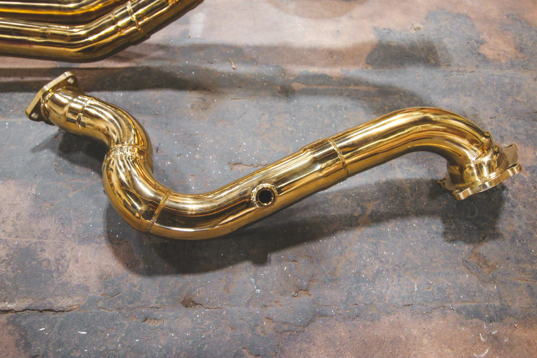 A close up view of Valvetronic Designs gold Valved Sport Exhaust Sytem pipe (for Audi RS6 / RS7 C7) on the ground.