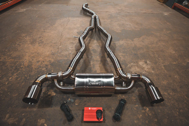 A top overview of Valvetronic Designs Brushed Valved Sport Exhaust System with valve controllers and wires on the ground (for Toyota Supra A90 / A91).