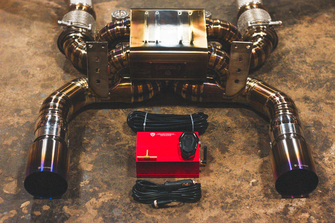 A close view of Valvetronic Designs Titanium Valved Sport Exhaust System with valve controller and wires on the ground (for Mclaren 720S).