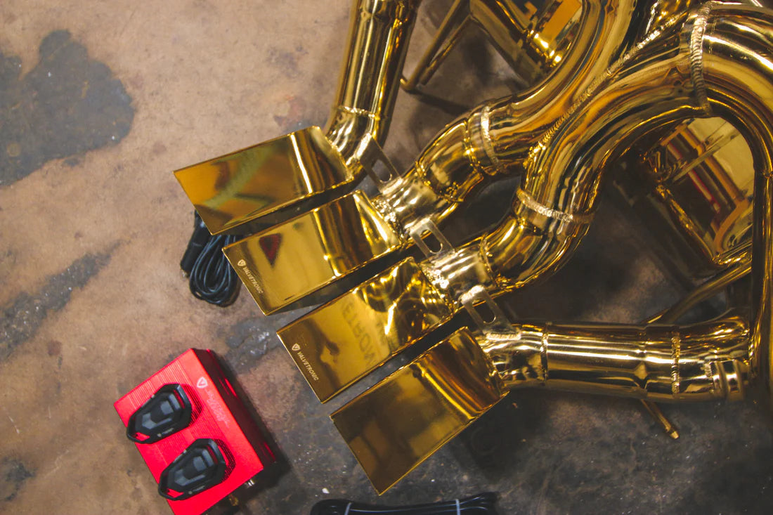 A close up view of Valvetronic Designs Valved Sport Exhaust System with valve controllers on the ground (for Lamborghini Aventador LP700 / SV).