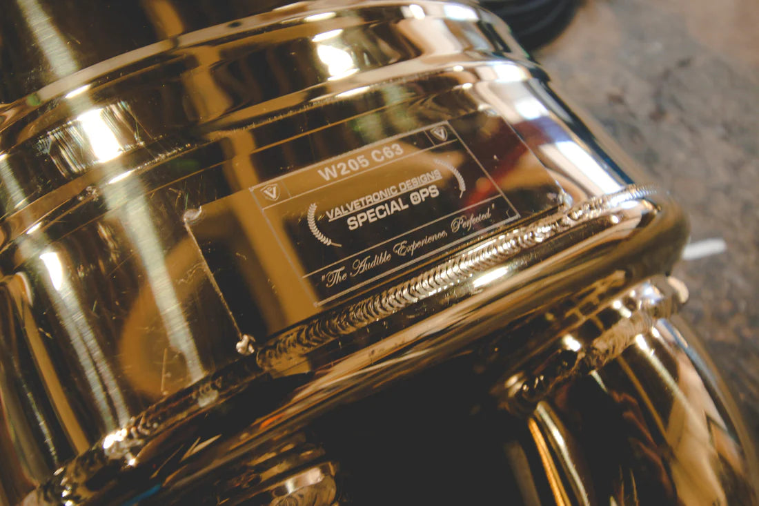 A close up view of Valvetronic Designs Stainless Steel Valved Sport Exhaust System's muffler on the ground (for Mercedes W205 C63 / C63s).