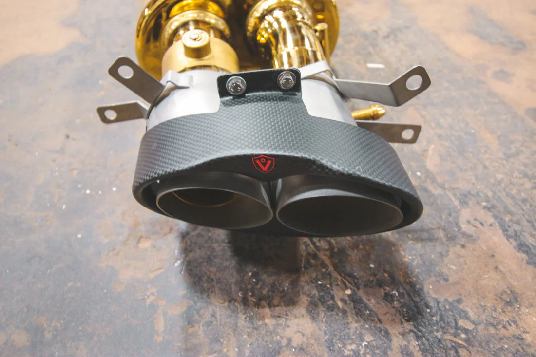 A close up of top part of pipes for Valvetronic Designs gold Valved Sport Exhaust Sytem (for Audi RS6 / RS7 C7) on the ground.